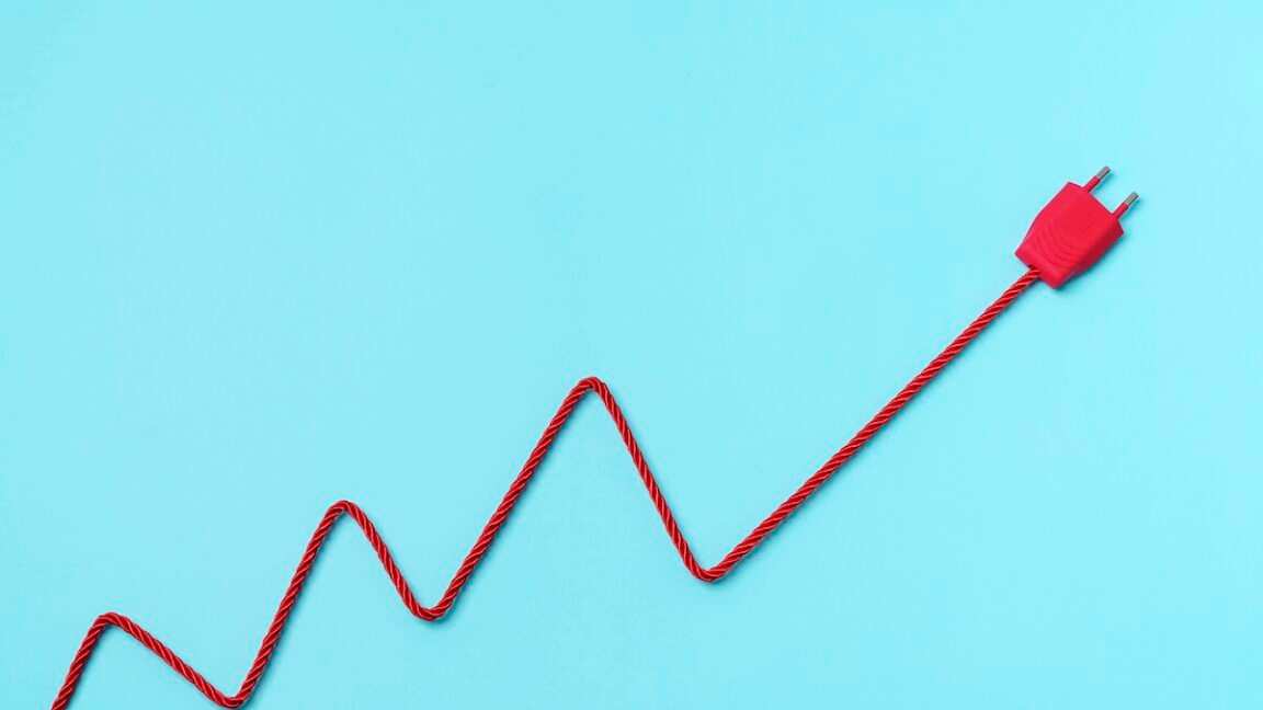 red electric power plug on blue background. increase to electricity prices concept.
