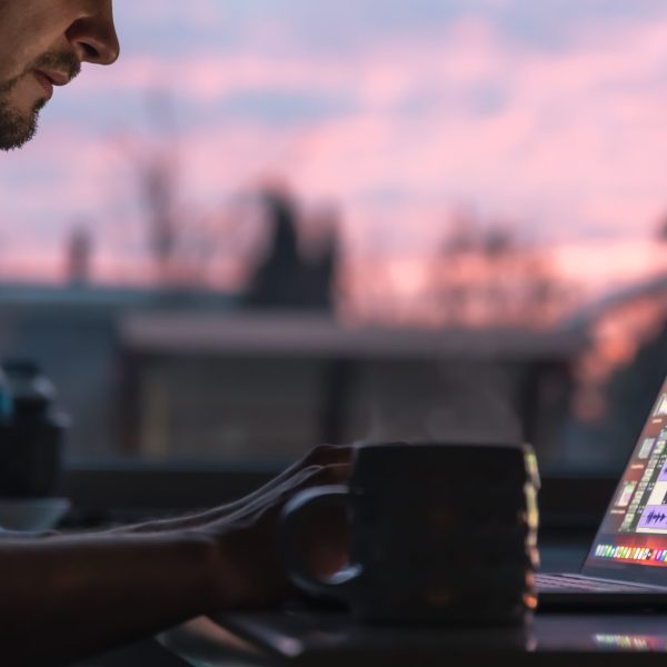 A male musician, arranger works with sound on a laptop in the dark early in the morning.